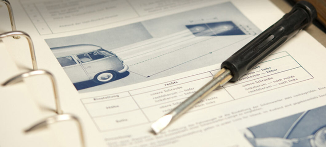 Ein Schreibenzieher liegt auf einem Dokument mit einer Abbildung eines VW-Busses.